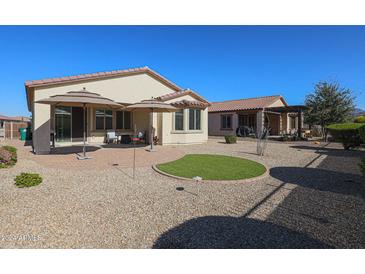 Relaxing backyard with patio, artificial turf, and umbrellas at 17915 W Silver Fox Way, Goodyear, AZ 85338