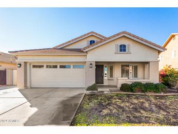 One-story house with tan exterior, two-car garage, and well-maintained landscaping at 8371 W Pontiac Dr, Peoria, AZ 85382