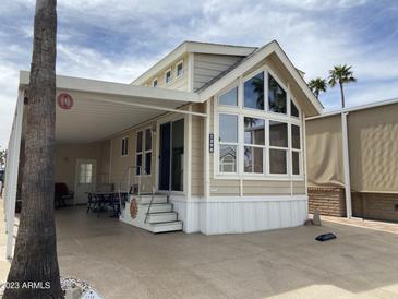 Tan single-wide manufactured home with covered patio and palm trees at 1398 S Cheyenne Dr, Apache Junction, AZ 85119