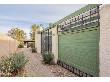 View of the property's exterior, including a gated entrance and a green garage door at 524 S Allred Dr, Tempe, AZ 85288