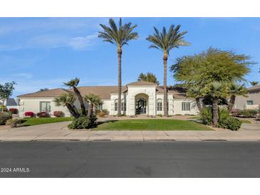 White stucco home with a tile roof, arched entryway, and lush landscaping at 9512 E Altadena Ave, Scottsdale, AZ 85260