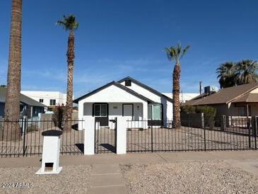 Newly renovated home with a white exterior, black accents, and a well-maintained front yard at 2114 W Washington St, Phoenix, AZ 85009