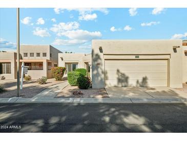 Tan stucco house with a two-car garage and landscaped front yard at 14444 W Moccasin Trl, Surprise, AZ 85374