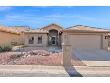 Beige house with a two-car garage and landscaped yard at 9209 E Emerald Dr, Sun Lakes, AZ 85248