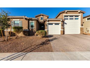 Tan two-story house with a three-car garage and landscaping at 17826 W Straight Arrow Ln, Surprise, AZ 85387