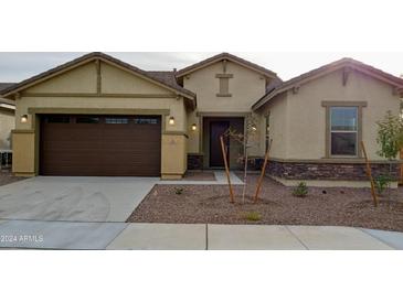 Tan house with brown garage door and stone accents at 21025 E Camina Buena Vis, Queen Creek, AZ 85142