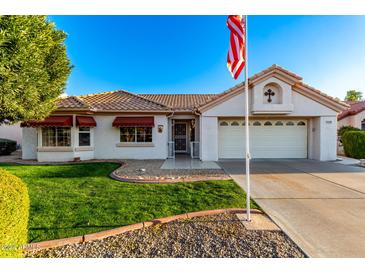 Single-story home with red awnings, landscaped lawn, and a two-car garage at 14105 W Sky Hawk Dr, Sun City West, AZ 85375