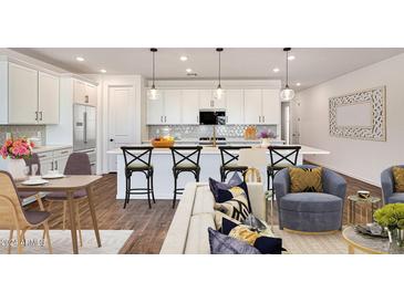 Open concept kitchen and living area with island, modern cabinetry, and hardwood floors at 17316 W Via Dona Rd, Surprise, AZ 85387