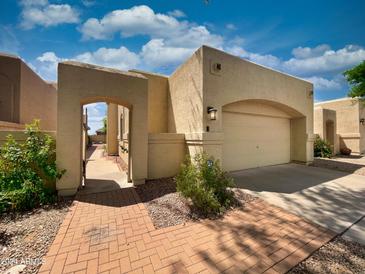 Tan stucco home with brick walkway, attached garage, and gated entry at 18802 N 44Th Pl, Phoenix, AZ 85050