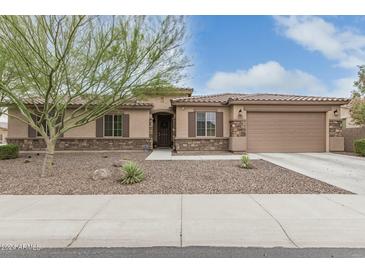 Inviting single-story home with a stone and stucco facade, a two-car garage, and a landscaped front yard at 5735 W Huntington Dr, Laveen, AZ 85339