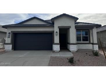 Charming single-story home with a dark gray garage door and white stone accents at 38085 W Excussare Way, Maricopa, AZ 85138