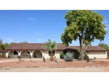 Inviting ranch-style home with arched entryways, desert landscaping, and a lush tree at 15414 N 41St St, Phoenix, AZ 85032