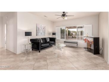 Living room with tile flooring, a ceiling fan, and large windows with shutters at 17994 N Verde Roca Dr, Surprise, AZ 85374