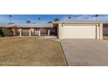 Front yard of a single-story home with attached garage, driveway, and landscaping at 10330 W Desert Forest Cir, Sun City, AZ 85351