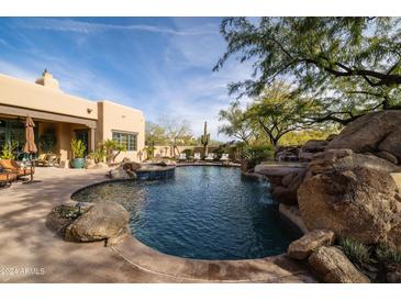 Inviting pool with a rock waterfall feature and surrounding patio at 33296 N Vanishing Trl, Scottsdale, AZ 85266