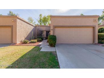 Tan stucco house with a two-car garage and well-manicured lawn at 9437 W Mcrae Way, Peoria, AZ 85382