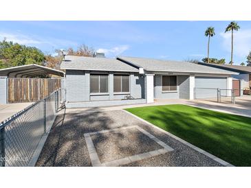 House exterior featuring a gray brick facade, artificial turf, and a two-car garage at 2264 E Holmes Ave, Mesa, AZ 85204