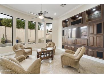 Living room with wicker furniture, built-in entertainment center, and large windows at 8146 E Wingspan Way, Scottsdale, AZ 85255