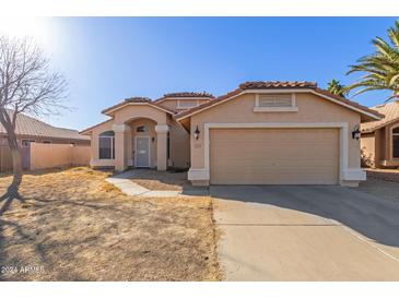 Tan house with a two-car garage and desert landscaping at 12479 W Palm Ln, Avondale, AZ 85392