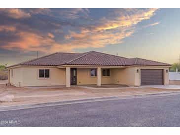 Tan house with brown garage door and tile roof at 115 Ironwood Pl, Wickenburg, AZ 85390