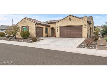 Single-story home with tan stucco exterior, brown garage doors, and landscaping at 18852 N 260Th Ln, Buckeye, AZ 85396