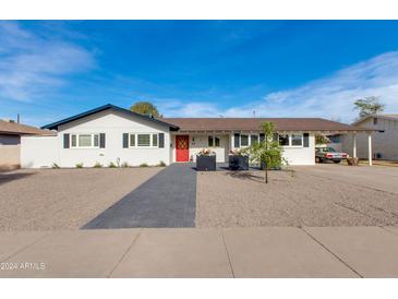 Charming single story home with red door, landscaped yard and paved walkway at 5110 E Verde Ln, Phoenix, AZ 85018