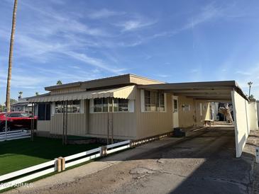 Tan mobile home with carport and artificial turf at 5201 W Camelback W Rd # D69, Phoenix, AZ 85031