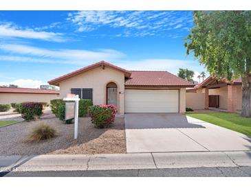 Tan stucco house with red tile roof, attached garage, and landscaping at 5203 E Saguaro Cir, Phoenix, AZ 85044