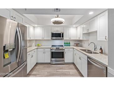 Modern white kitchen with stainless steel appliances and granite countertops at 4200 N Miller Rd # 309, Scottsdale, AZ 85251
