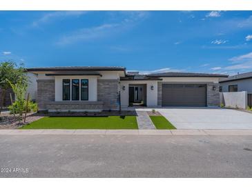 Single-story home with stone and stucco exterior, two-car garage, and landscaped front yard at 21875 E Misty Ln, Queen Creek, AZ 85142