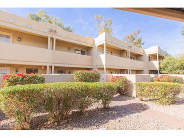 Light beige stucco building with red flowering bushes and a brick pathway at 1425 E Desert Cove Ave # 32, Phoenix, AZ 85020