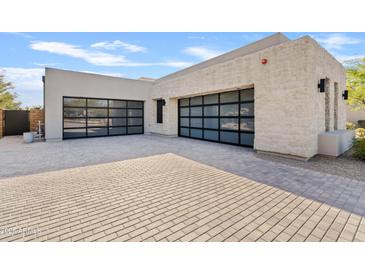 Modern home with stone and stucco exterior, featuring a large two-car garage and a paved driveway at 8849 E Via Del Sol Dr, Scottsdale, AZ 85255