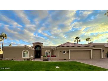 Single-story home with a tile roof, landscaped lawn, and a three-car garage at 8689 E Windrose Dr, Scottsdale, AZ 85260
