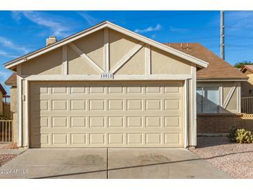 Tan house with a two-car garage and a neatly landscaped front yard at 10018 N 66Th Ln, Glendale, AZ 85302