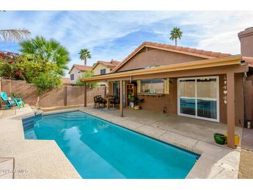 Inviting backyard oasis featuring a refreshing pool, covered patio, and dining area at 4636 E Danbury Rd, Phoenix, AZ 85032
