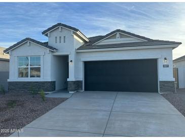 White house with a black garage door and stone accents at 18377 W Desert Hollow Dr, Wittmann, AZ 85361