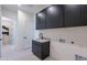 Modern laundry room featuring dark cabinetry and a utility sink at 28415 N 59Th Way, Cave Creek, AZ 85331