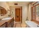 Spa-like bathroom with soaking tub, double vanity, and wooden cabinetry at 10040 E Happy Valley Rd # 676, Scottsdale, AZ 85255