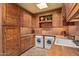 Functional laundry room with wooden cabinets and a large utility sink at 10040 E Happy Valley Rd # 676, Scottsdale, AZ 85255
