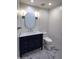 Contemporary bathroom with dark vanity, marble flooring, and an oval mirror at 7175 E Camelback Rd # 704, Scottsdale, AZ 85251