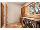 Laundry room with wooden cabinets, stone flooring, and washer/dryer at 28080 N 101St St # 116, Scottsdale, AZ 85262
