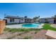 Backyard oasis featuring a kidney-shaped pool, storage shed, and grassy area at 2024 N Miller Rd, Scottsdale, AZ 85257