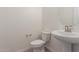 Powder room with pedestal sink, toilet, and oval mirror at 21726 E Lords Way, Queen Creek, AZ 85142