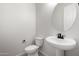 Clean and modern powder room with pedestal sink and oval mirror at 21673 E Roundup Way, Queen Creek, AZ 85142