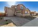 Front exterior of a home with stone accents, desert landscaping, and a three-car garage at 21665 E Roundup Way, Queen Creek, AZ 85142