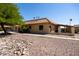 Tan stucco exterior of home with Spanish tile roof and mature tree at 1972 S Clubhouse Dr, Casa Grande, AZ 85194