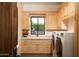 Convenient laundry room with light wood cabinets, a washer and dryer, and a window at 10728 E Cottontail Ln, Scottsdale, AZ 85255