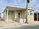 Tan mobile home with covered porch, decorative railing, and palm trees at 241 S Aquamarine Dr, Apache Junction, AZ 85119