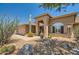 Tan house with a two-car garage, arched entryway, and desert landscaping at 9768 E Balancing Rock Rd, Scottsdale, AZ 85262