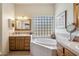 Spa-like bathroom featuring double vanities, a large soaking tub and a glass block window at 43908 N 10Th St, New River, AZ 85087